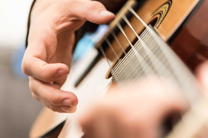 Zupfhand an der Gitarre
