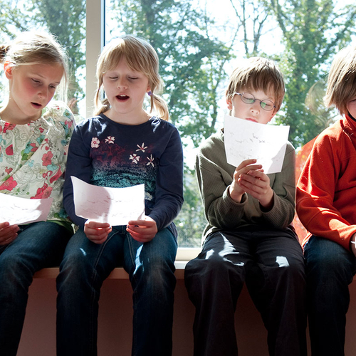 Vier Kinder sitzen auf einer Fensterbank und singen