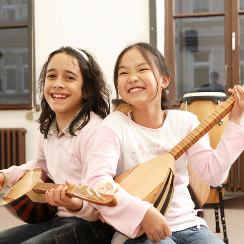 Zwei Kinder spielen auf exotischen Zupfinstrumenten